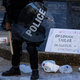 Police officers in riot gear stand in and around the milk jugs broken by two men moments earlier on May 30, 2020, in Louisville, Ky.